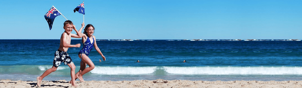 Children running on an Australian beach with Australian flags